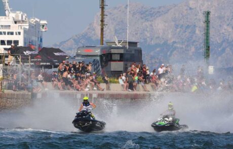 Two jet skis spray audience with water as they race past.