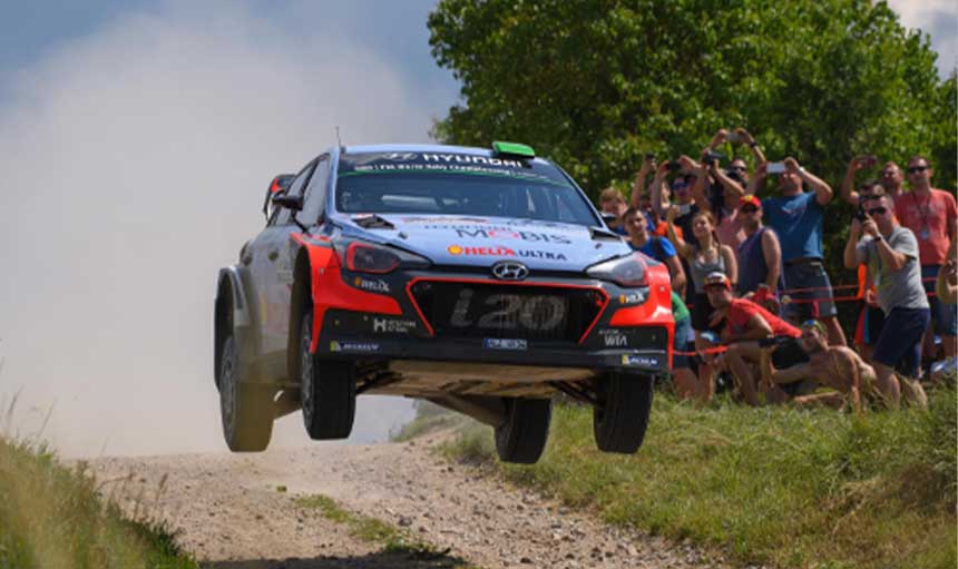 A rally car flies through the air as it races past onlookers.